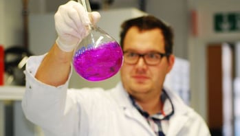 scientist holding vial with purple liquid